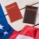 American flag and passports on wood. USA flag and two passports on white wooden background close up, horizontal image.