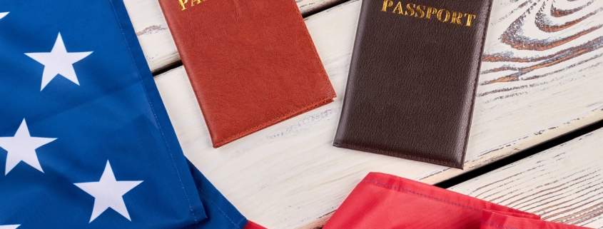 American flag and passports on wood. USA flag and two passports on white wooden background close up, horizontal image.