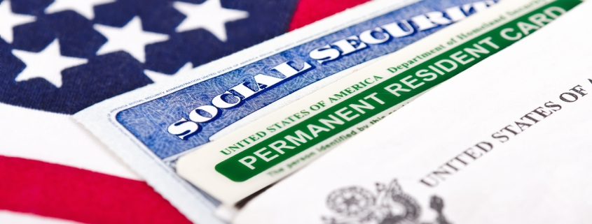 United States of America social security and green card with US flag on the background. Immigration concept. Closeup with shallow depth of field.