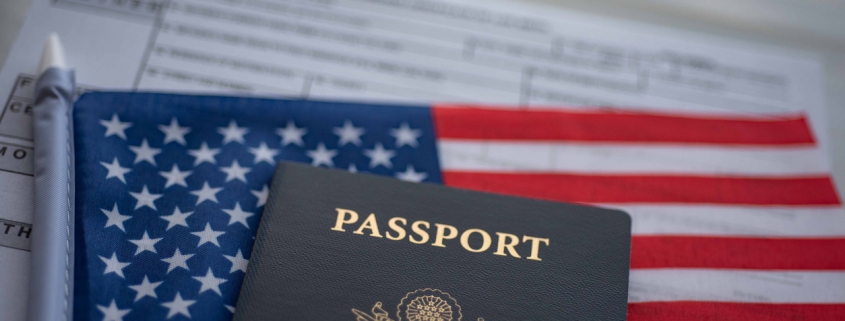 Blurred U.S. standard application certificate of live birth application form next to American flag and Passport of USA. Close up view.