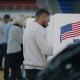 Elderly male voter with bulletin in hands comes to voting booth. Multicultural American citizens come to vote in polling station. Political races of US presidential candidates. National Election Day.