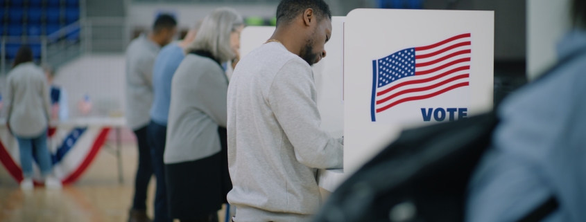 Elderly male voter with bulletin in hands comes to voting booth. Multicultural American citizens come to vote in polling station. Political races of US presidential candidates. National Election Day.