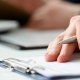 Hand of businessman in suit filling and signing with silver pen partnership agreement form clipped to pad closeup. Management training course, some important document, team leader ambition concept