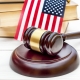 Judge's gavel with books and american flag on white wooden table.