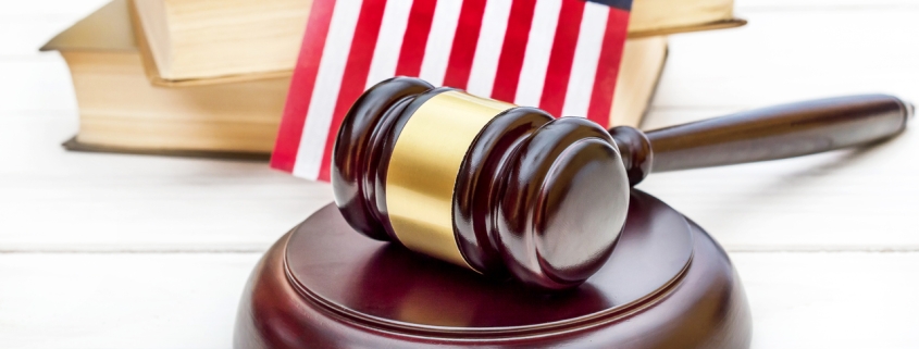 Judge's gavel with books and american flag on white wooden table.