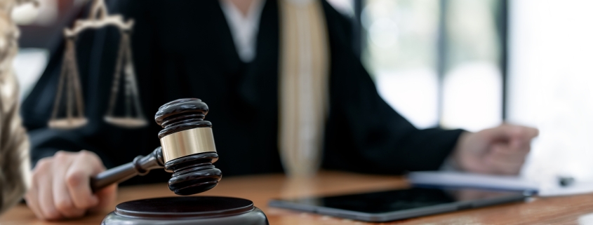 Woman judge hand holding gavel to bang on sounding block in the court room.