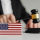 Judge's hand holding wooden gavel. Flag of USA. Concept of USA justice system