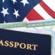 United States of America permanent resident card, green card, displayed with a US flag in the background and a passport in the foreground. Immigration concept.