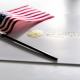 U.S. Citizenship and Immigration Services envelope, white folder for naturalization certificate on table with American flag