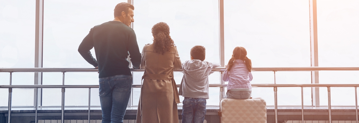 Full length of family with two little kids looking at the flying airplane