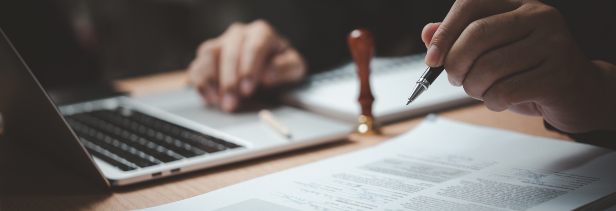 Man hand stamping approval signing on document or paperwork contract at desk.