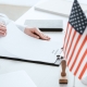 cropped view of woman holding document with immigration reform lettering near american and european flags