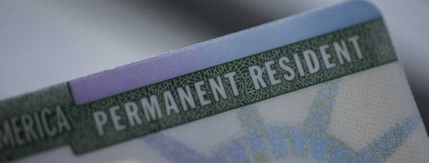 Close up view of Fragment of Permanent resident card (Green) card of USA on blurred background.