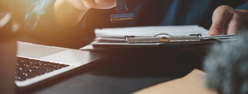 Man stamping approval of work finance banking or investment marketing documents on desk.